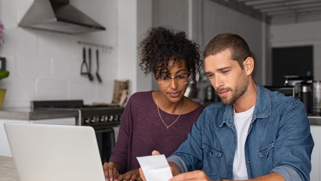 Couple in kitchen, using a laptop